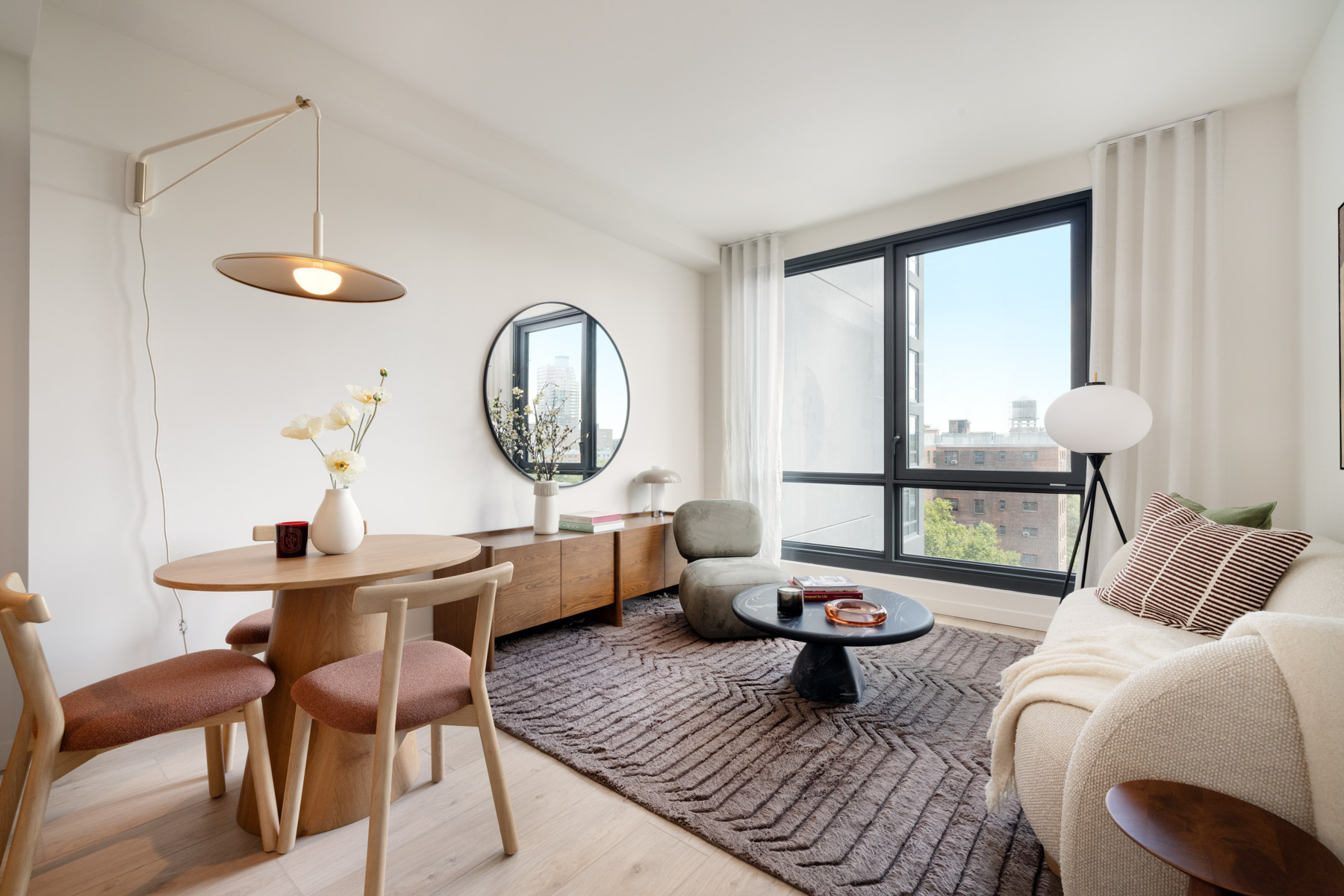 Bright living room with seating, large mirror on wall and large windows