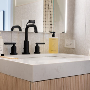 Bathroom sink detail showing London Grey Stone Countertops with dark fixtures