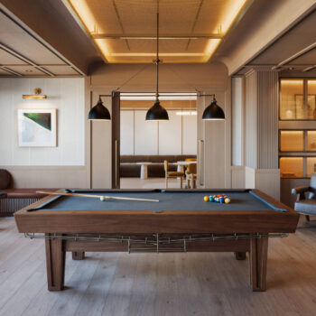 Straight-on view of a luxury billiards room highlighting a dark felt pool table, built-in lighted shelving units, a leather bench with small white side tables, and elegant wood paneling.