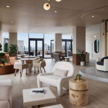 Beautifully curated sunset lounge featuring low-profile contemporary armchairs, natural wood block side tables, and glass doors opening directly onto an outdoor deck.